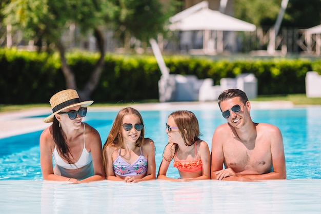 Foto feliz familia de cuatro en la piscina al aire libre