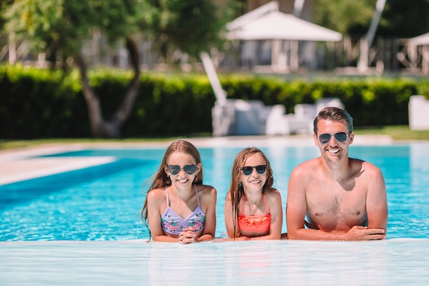 Feliz familia de cuatro en la piscina al aire libre