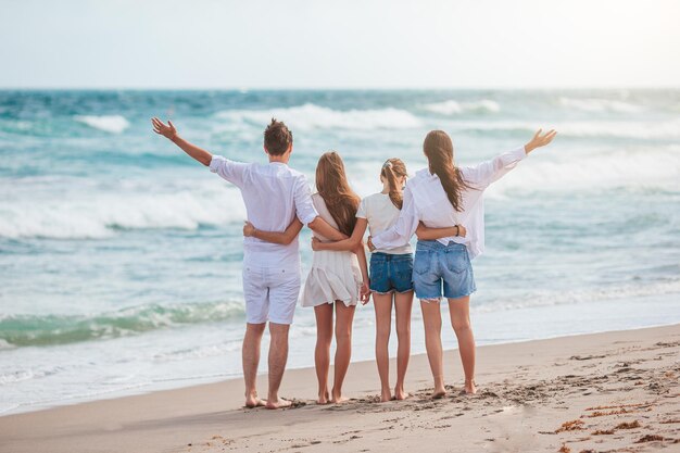 Feliz familia de cuatro en la playa en las vacaciones de verano