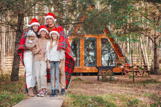 Feliz familia de cuatro con sombrero de Santa disfrutando de las vacaciones de Navidad. Padre con hijos envueltos en una manta