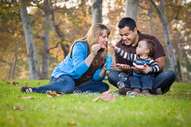 Foto feliz familia étnica de raza mixta jugando con burbujas en el parque