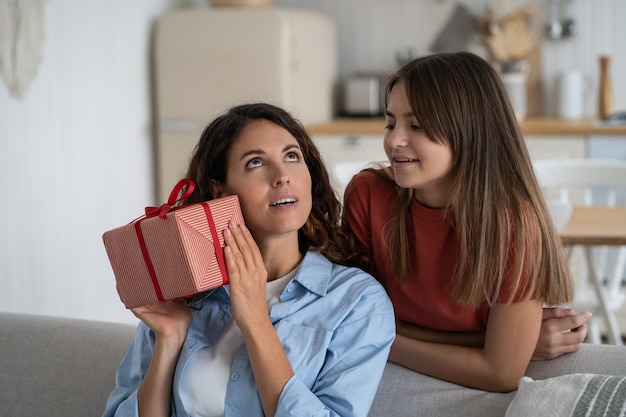 Feliz familia festiva de mujer y adolescente dando caja de regalo a la madre en vacaciones o cumpleaños