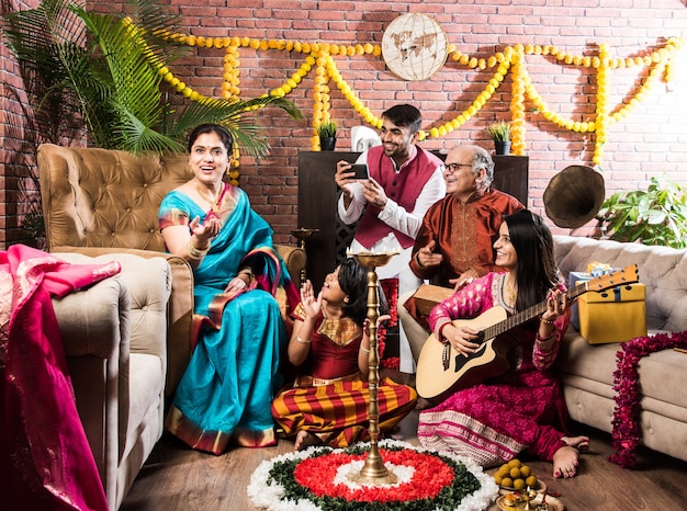 Feliz familia india cantando, tocando música, guitarra mientras celebra festivales con telas tradicionales