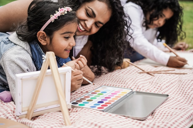 Feliz familia india divirtiéndose pintando con niños al aire libre en el parque de la ciudad