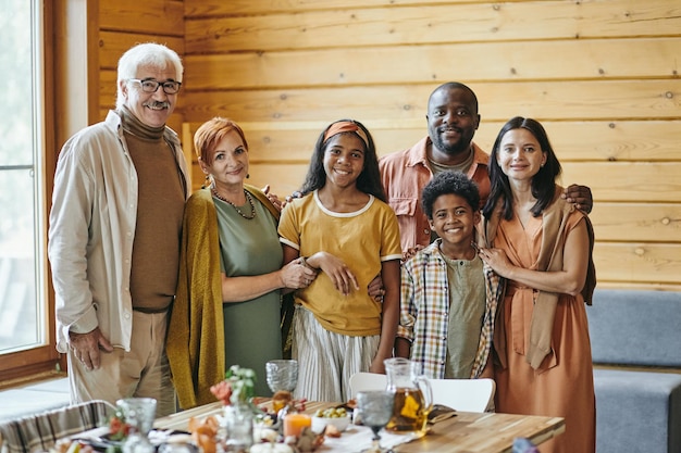 Feliz família inter-racial de seis pessoas em pé na mesa festiva servida