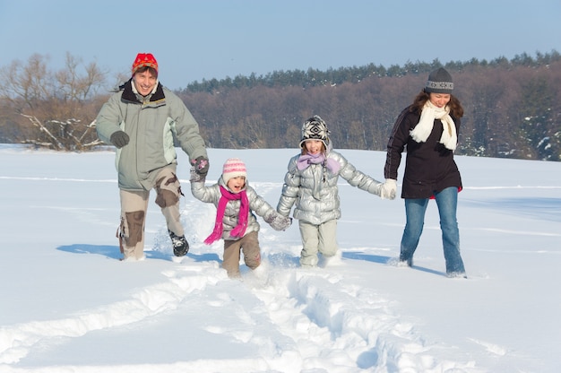 Feliz familia invierno diversión al aire libre. Padres sonrientes con niños jugando con nieve en vacaciones de invierno