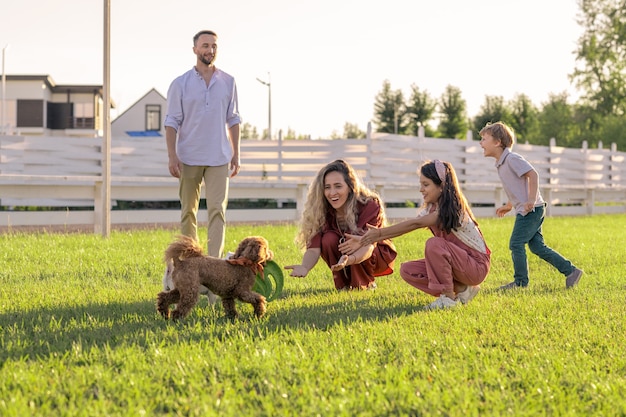 Feliz familia joven de cuatro divirtiéndose con su mascota