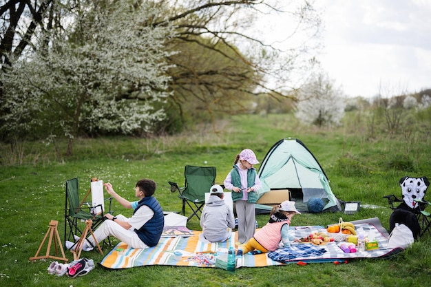 Feliz familia joven cuatro niños divirtiéndose y disfrutando al aire libre en un picnic