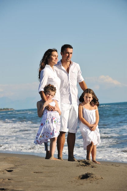 feliz familia joven vestida de blanco diviértete de vacaciones en una hermosa playa