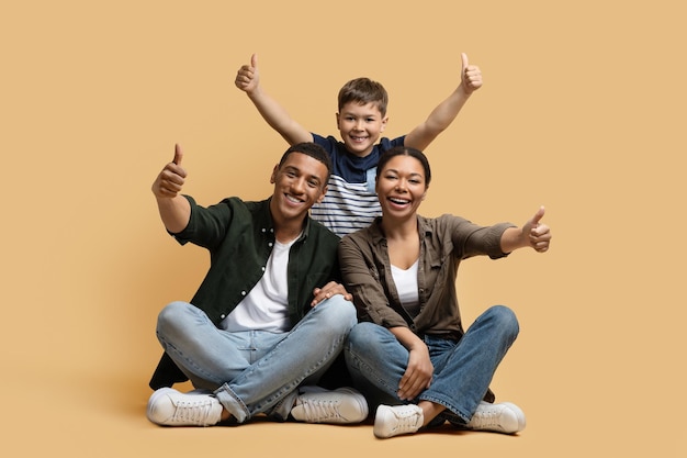 Foto feliz familia linda padres e hijo mostrando pulgar hacia arriba