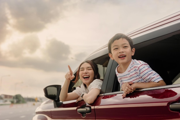 Feliz familia madre e hijo van a un viaje de verano en el auto en la autopista al atardecer