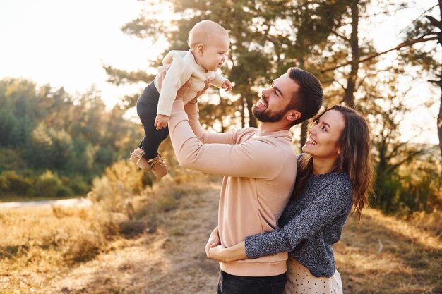 Feliz familia de madre familia y pequeño bebé descansa al aire libre Hermosa naturaleza soleada de otoño