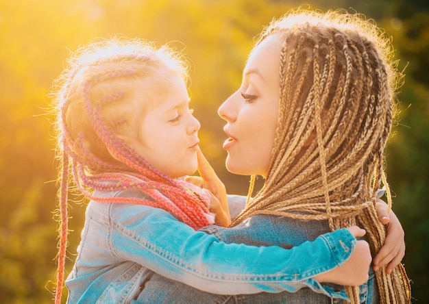 Feliz família mãe e filha criança abraçando e beijando