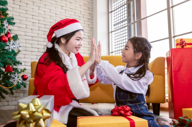 Feliz família mãe e filha filha fazendo e dando presentes na época do Natal.