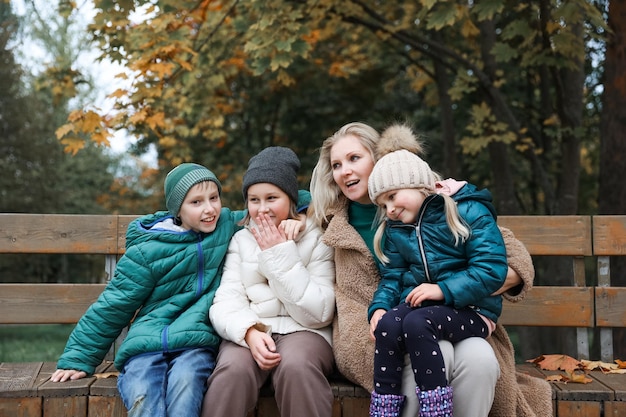 Feliz família mãe e filhos estão no parque da cidade do outono Eles posam sorrindo brincando e se divertindo Árvores amarelas brilhantes