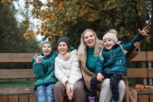 Feliz família mãe e filhos estão no parque da cidade do outono Eles posam sorrindo brincando e se divertindo Árvores amarelas brilhantes