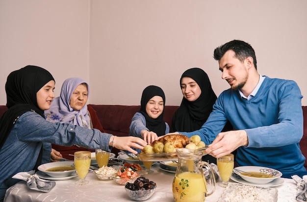 Feliz família muçulmana jantando iftar durante a mesa de jantar do Ramadã em casa