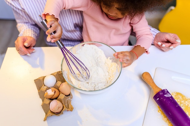Feliz familia multiétnica cocinando pasteles juntos en la cocina