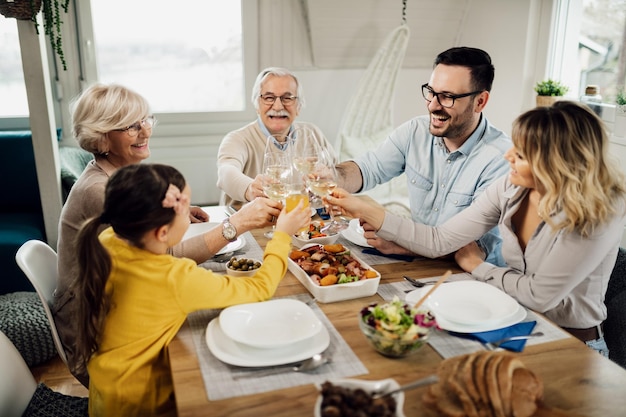 Feliz familia multigeneracional divirtiéndose mientras brinda con bebidas durante un almuerzo