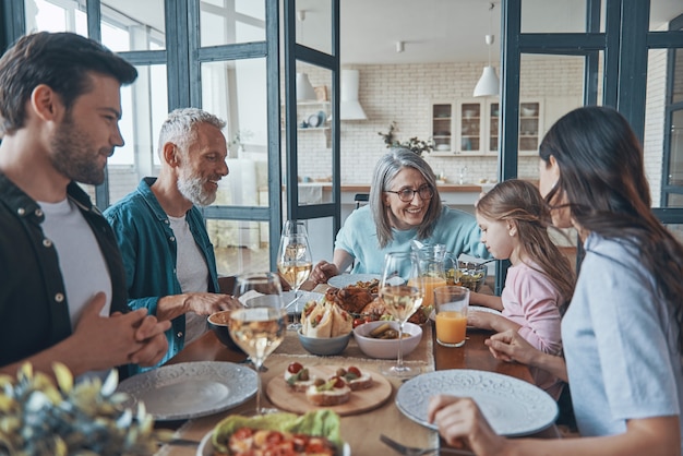 Feliz familia multigeneracional sonriendo mientras cenan juntos