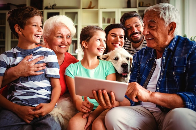 Feliz familia multigeneracional con tableta digital en la sala de estar