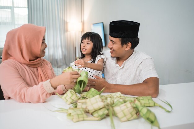 Feliz familia musulmana asiática haciendo ketupat juntos en casa antes del eid mubarak