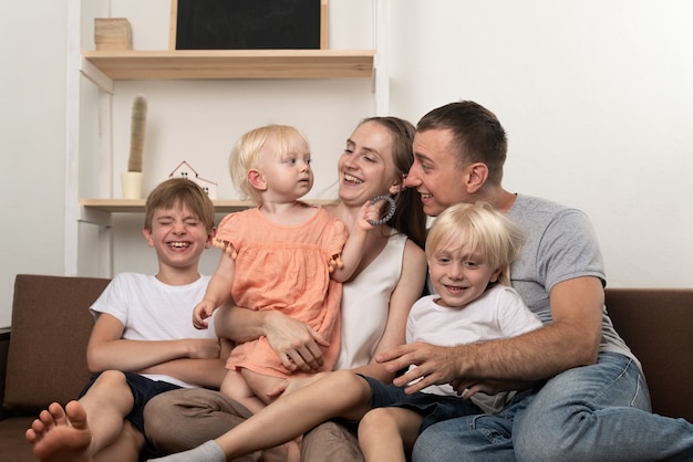 Feliz familia numerosa en casa. Los padres y tres niños pequeños son divertidos.