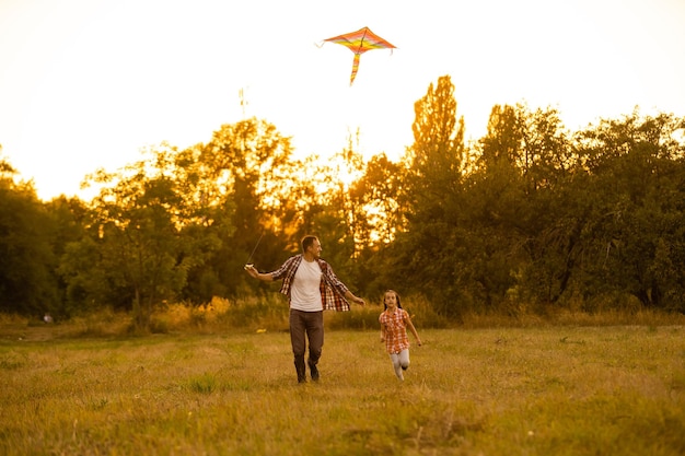 feliz família pai e filha criança correr com uma pipa no Prado