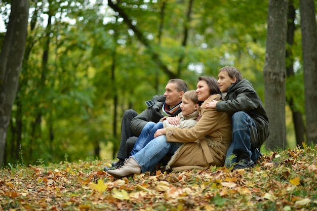 Feliz família sorridente sentada nas folhas na floresta de outono