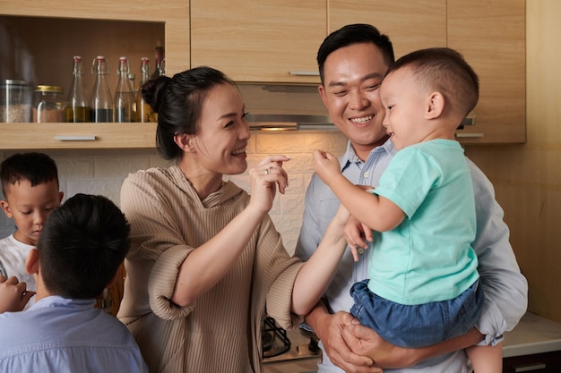 Feliz familia vietnamita con tres hijos parados juntos en la cocina