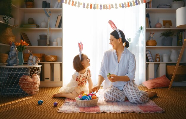 Feliz feriado Mãe e filha com ovos de pintura Família celebrando a Páscoa