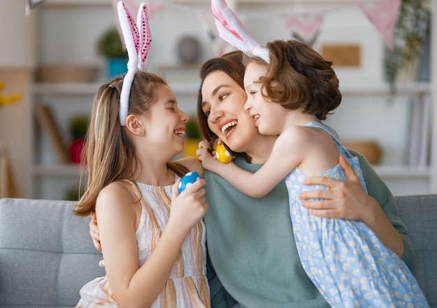 Feliz feriado, mãe e filhas pintando ovos. Família comemorando a Páscoa