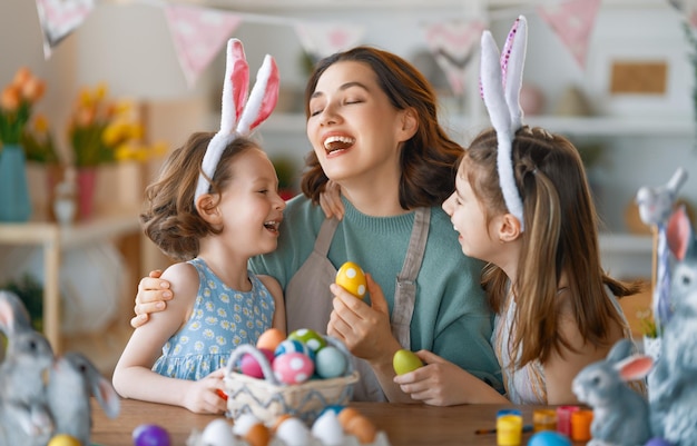 Feliz feriado Uma mãe e suas filhas estão pintando ovos Família se preparando para a Páscoa