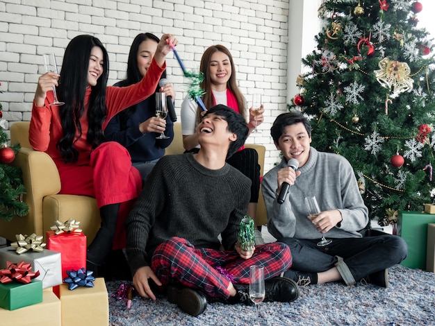 Feliz festa de jovens asiáticos com beber vinho e cantar uma música em casa para comemorar o festival de Natal. Celebração de ano novo em casa. Feliz Natal e boas festas de gangue teen thai.