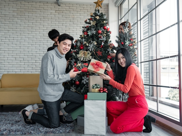 Feliz festa do grupo de jovens asiáticos com presentes em casa para comemorar o festival de natal. adolescentes tailandeses comemoram o natal e o ano novo. feliz natal e boas festas.