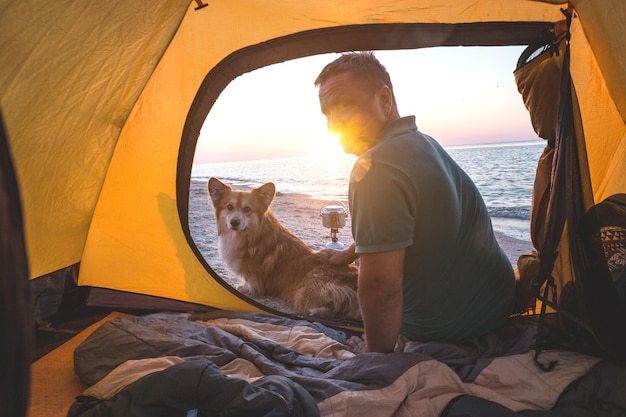 Feliz fim de semana à beira-mar - homem com um cachorro em uma barraca na praia ao amanhecer. Paisagem ucraniana no Mar de Azov, Ucrânia