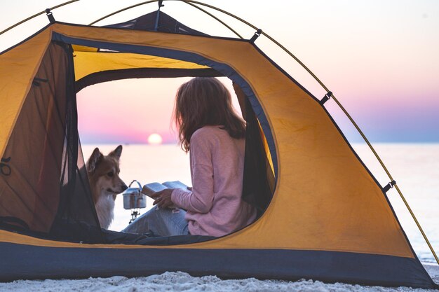 Feliz fin de semana junto al mar - niña con un perro en una carpa en la playa al amanecer. Paisaje ucraniano en el mar de Azov, Ucrania