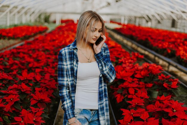 Feliz florista de avental trabalhando em floricultura e falando no celular enquanto segura notas na mão