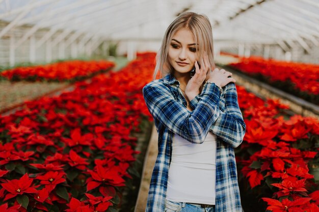 Feliz florista de avental trabalhando em floricultura e falando no celular enquanto segura notas na mão