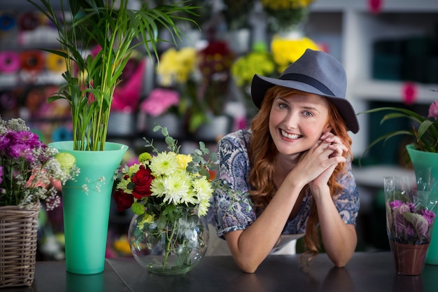 Feliz florista femenina inclinada en florería