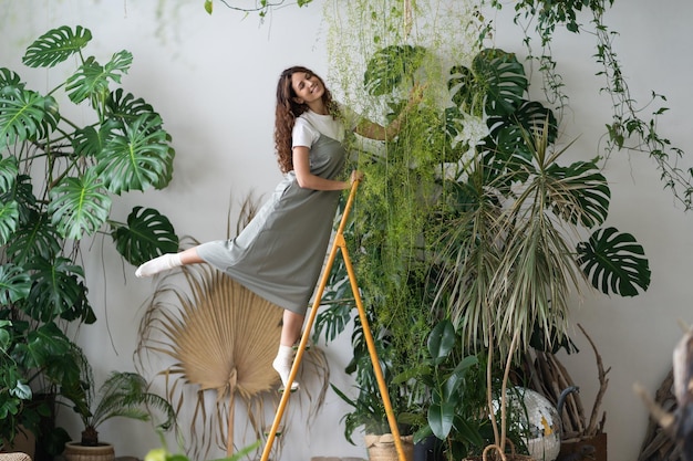 Feliz florista feminina na escada com ternura preparando plantas de casa para venda jardinagem interna