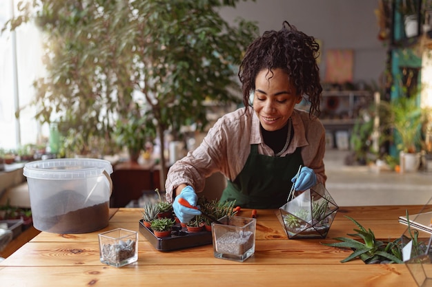 Feliz florista sorridente fazendo composição de plantas suculentas no estúdio de design floral