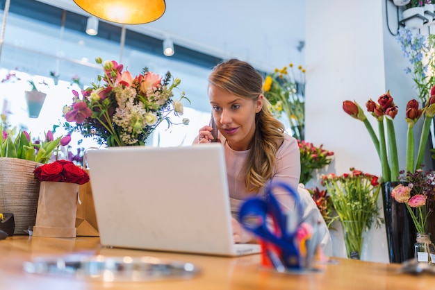 Feliz florista utilizando tecnologías en la tienda de flores