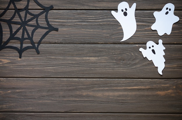 Feliz fondo de vacaciones de halloween con papel artesanal en forma de fantasmas y telarañas en la mesa de madera