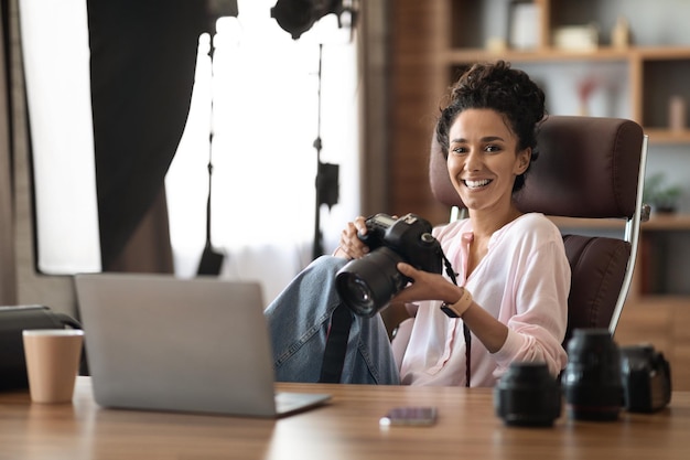 Foto feliz fotógrafa milenar trabalhando no escritório