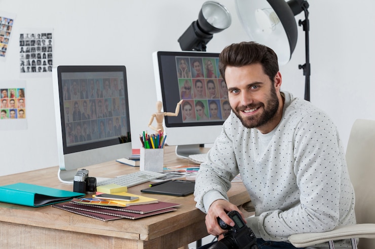 Foto feliz fotógrafo con cámara en su escritorio
