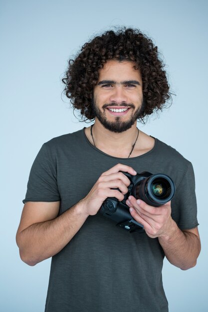 Feliz fotógrafo sosteniendo una cámara en el estudio