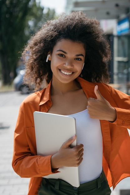 Feliz freelancer emocional segurando o computador portátil, aparecendo o polegar