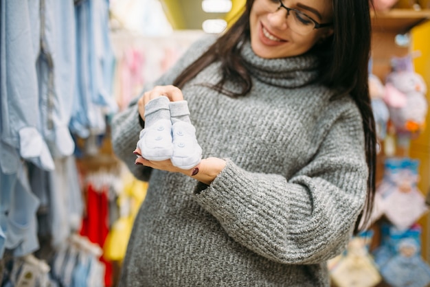 Feliz futura mãe compra roupas de criança