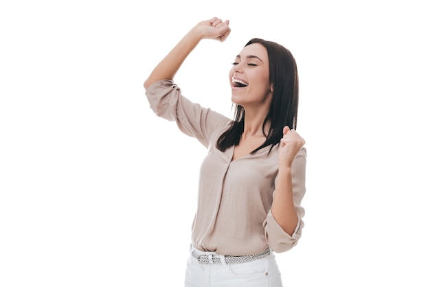 Feliz ganador. Hermosa mujer joven en ropa casual elegante gesticulando y mirando feliz mientras está de pie contra el fondo blanco.